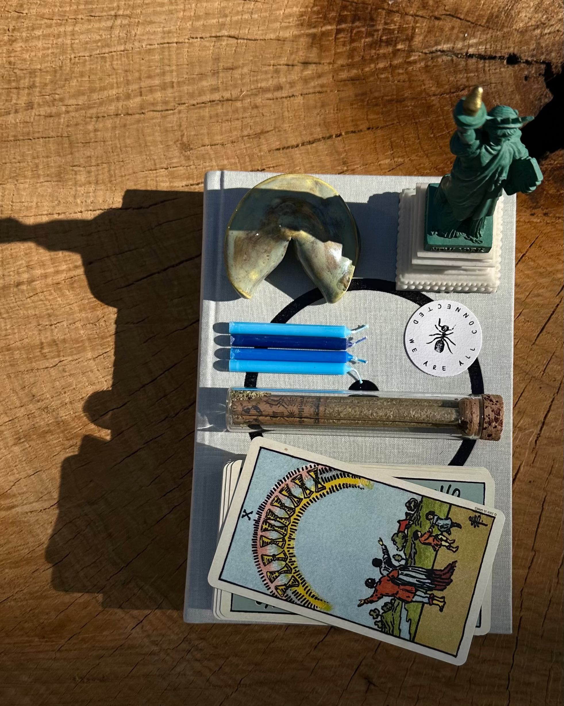 Collection of rollers, tarot cards, a statue, and other items on a wooden surface